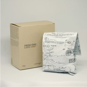 A package of fresh beans beside a box of Somage Loose Leaf Chai, featuring organic spices and premium black tea ingredients.